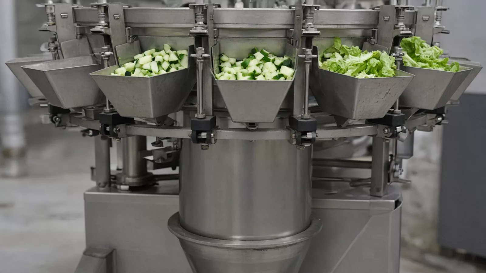 Stainless buckets holding diced cucumber and lettuce leaves above a plain metal cone
